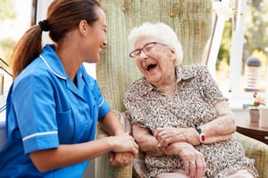 Senior woman laughing along with a nurse in a senior living community