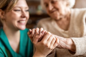 Close photo of a senior woman holding hands with a nurse