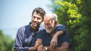 Adult son hugging senior father outdoors