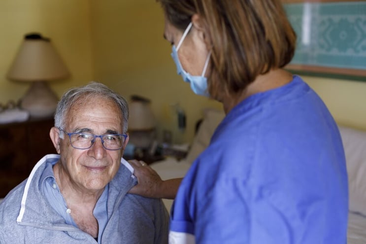 Caregiver with a mask assisting a senior