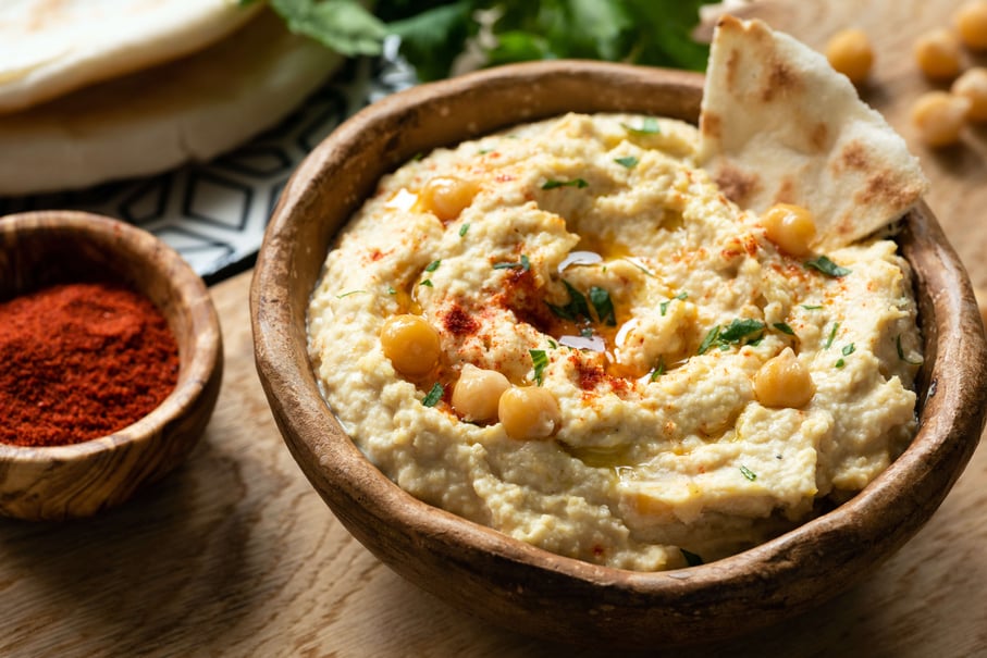 Chickpea hummus in bowl served with a side pita bread