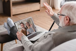 Elderly male video chatting with a couple on laptop