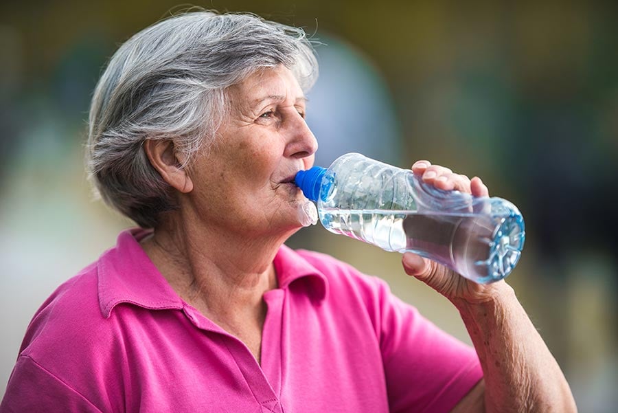Elderly woman drinking a water bottle outside