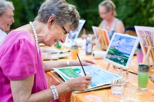 Elderly woman watercolor painting with a group outside