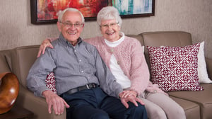 Elderly couple smiling while sitting on a couch