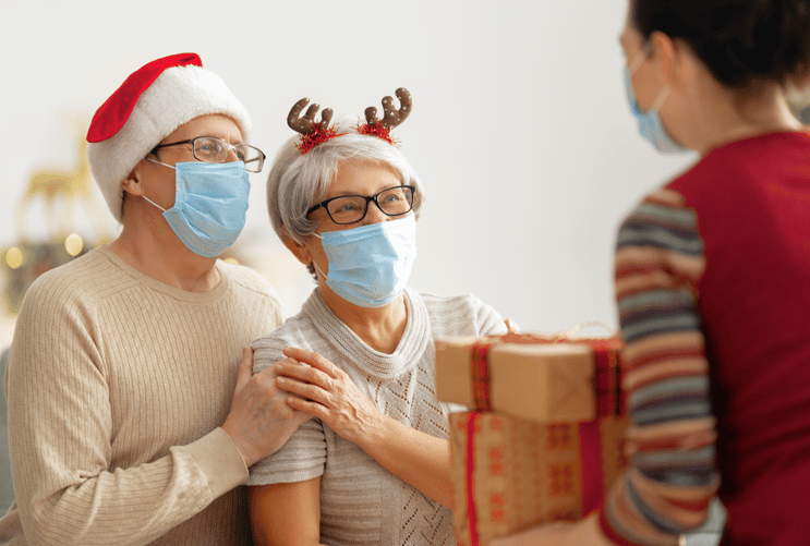 Senior couple receiving Christmas gifts from medical staff member