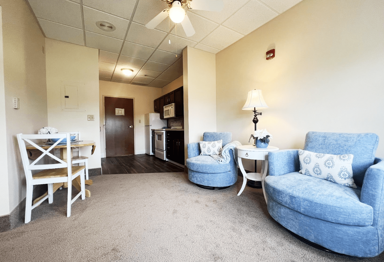 model suite with two blue swivel chairs on the right and a dining room table on the left.